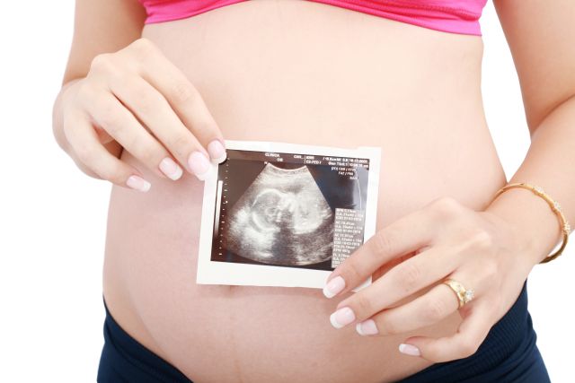 Pregnant woman's belly and ultrasound over white background.